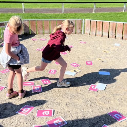 2 piger der løber rundt mellem bogstaver
